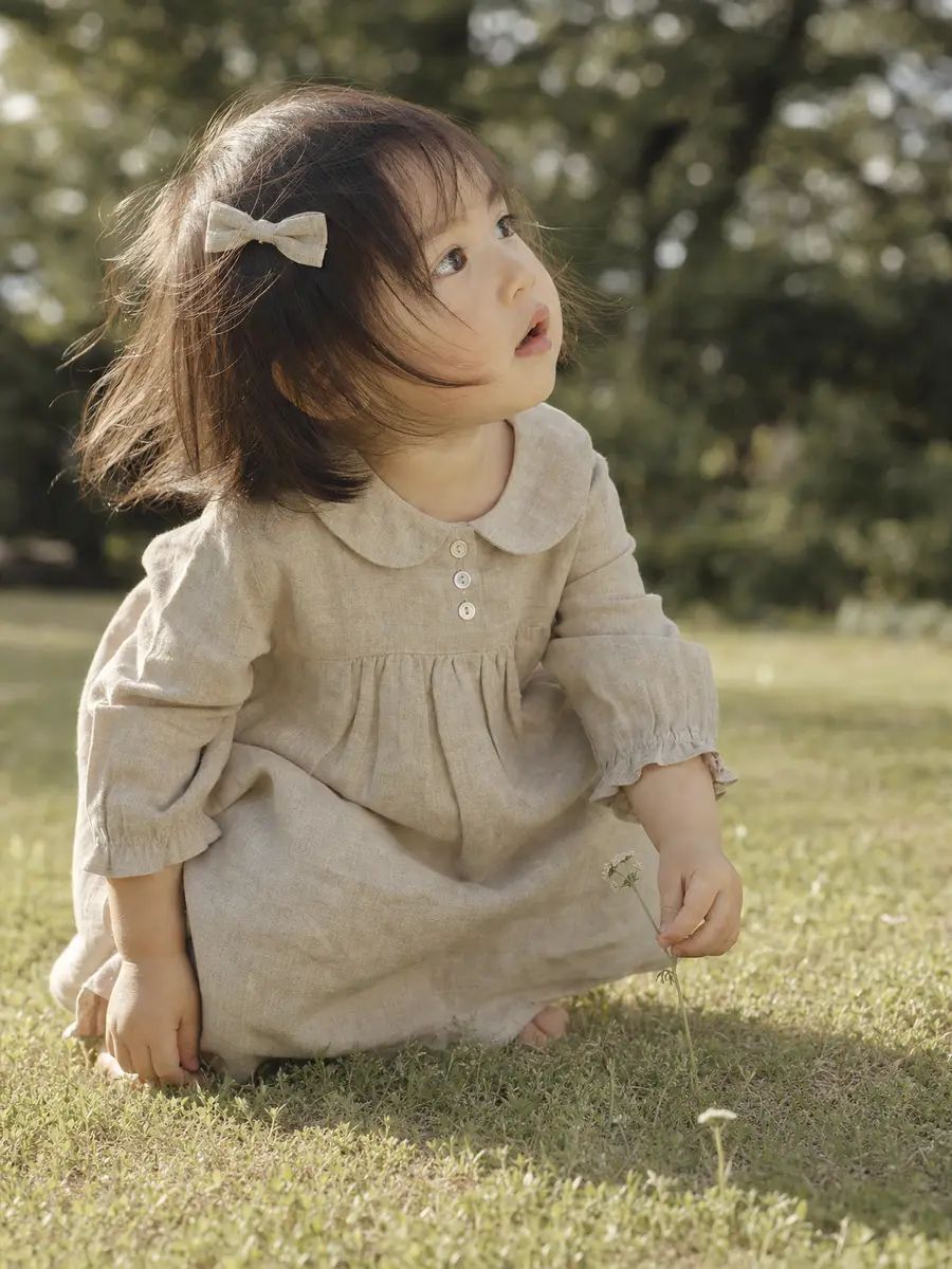 リネンワンピースの女の子、自然光の庭で
